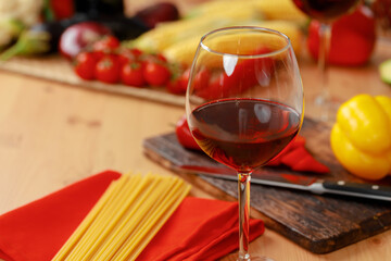 Glass of red wine and dry spaghetti on kitchen table