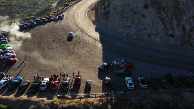 Done shot of a Dodge Challenger with muscle and sports cars doing doughnuts and burnouts with a car club in the Angeles National Forest in Southern California