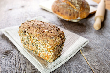Home made sourdough bread with dried sunflower and pumpkin seeds on rough board background. Copy space.