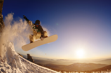 Snowboarder jumping against the sunset sky