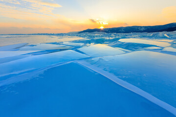 Transparent blue hummocks Baikal ice is shining through the crack sunset