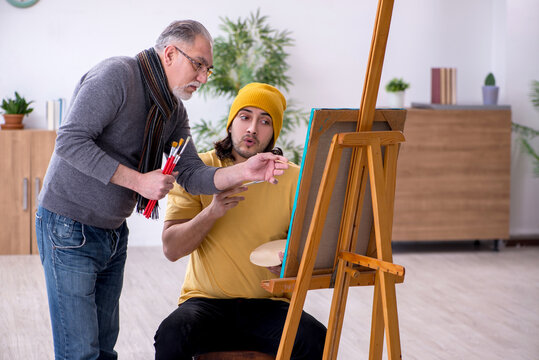 Young man taking lesson from old painter
