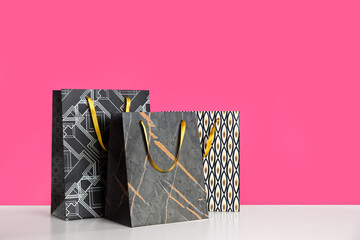 Gift bags on white table against pink background