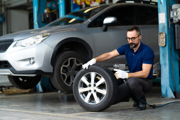 Obraz na płótnie Canvas Professional car mechanic changing car wheel at Car maintenance and auto service garage.