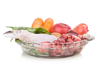 Ingredients of barf raw food recipe for dogs consisting meat, organs, fish, eggs and vegetable in white background