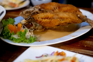 Close up of deep fried fish with fish sauce on the white plate.