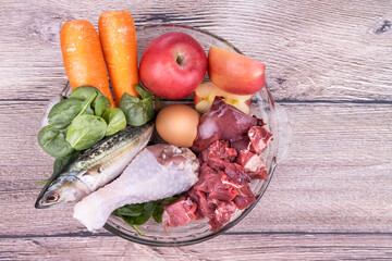Overhead view on Ingredients of barf raw food recipe for dogs consisting meat, organs, fish, eggs and vegetable
