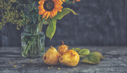 Autumn still life with flowers, leaves and fruit on the dark background.