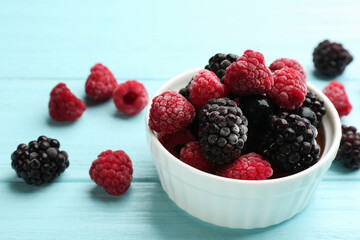 Tasty frozen blackberries and raspberries on light blue wooden table. Space for text