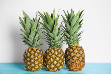 Fresh ripe juicy pineapples on light blue wooden table