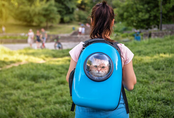 woman walking with a cat in a backpack