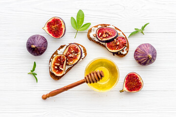 Sandwiches with figs, cheese and honey on table