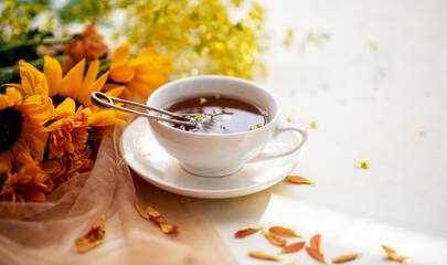 Naklejka na ściany i meble Autumn, fall leaves, flowers hot cup of herbal tea on wooden rustic background. Seasonal, morning tea. Sunday relaxing and still life concept. Toned image. Copy space.
