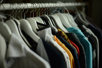 sweaters and hooded shirts hanging on coathangers on a clothing rack in a row