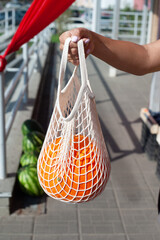 Unrecognizable young woman's hand holding an eco-bag with pomelo. Zero waste concept