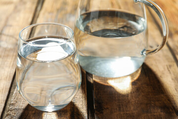 Glass of water on wooden table, closeup. Refreshing drink