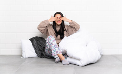 Young Colombian girl in pajamas at indoors covering eyes by hands