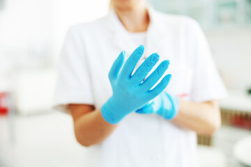 Closeup of lab assistant putting on sterile rubber gloves.