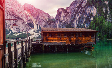 Lago di Braies, Italy. Panoramic view of the lake. Boat hut with mountains on background. Colorful summer sunrise of Italian Dolomite Alps, Europe. Traveling concept background. Toned image.