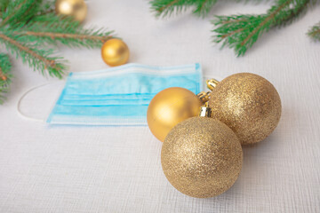 Medical mask, Christmas balls, green spruce branches. New year concept during a pandemic, protect yourself from coronavirus, there is a place for text, on a white background