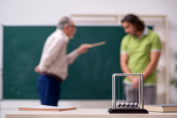 Old professor physicist and young student in the classroom