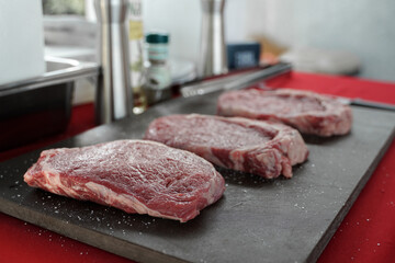 Selective focus on front fresh raw Prime beef steaks on board ready for seasoning  in the kitchen