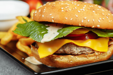 burger with cutlet, cheese and tomatoes. With french fries and burger sauce