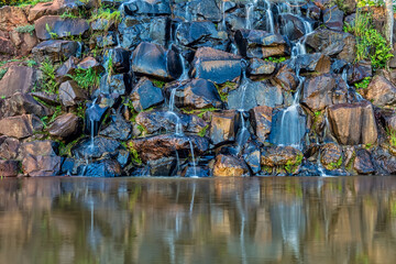 Waterfall of stones reflecting in the lake ahead. Wallpaper of cascade of stones and lake