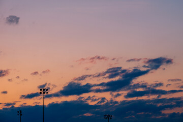 Silhouette of poles or column of spotlight or stadium light in arena with sunset beautiful sky cloud and with copy space.