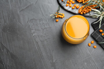 Sea buckthorn juice and fresh berries on black table, flat lay. Space for text