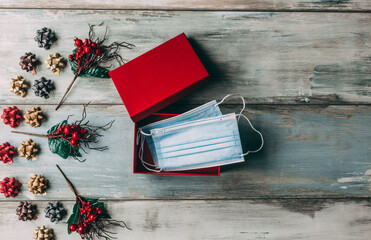 Christmas ornaments and face masks in gift box on wooden background. Covid-19 and holiday concept. © Robert Petrovic