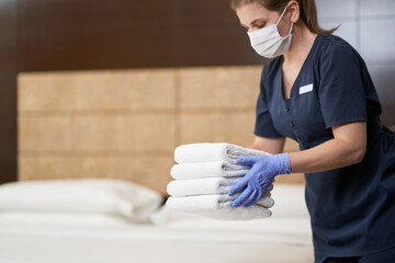 Housemaid preparing clean towels in the cleaned room