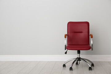 Comfortable office chair near light wall indoors. Space for text