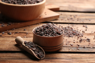 Black salt in bowl and scoop on wooden table