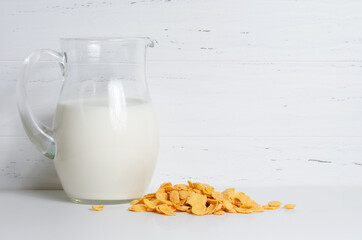 Milk in a glass jug and corn flakes. The concept of natural and healthy food. White background....