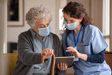 Senior woman and nurse using digital tablet at home during consult - Powered by Adobe