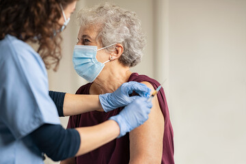 Doctor giving Covid vaccine to senior woman - obrazy, fototapety, plakaty