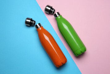 Modern thermo bottles on color background, flat lay
