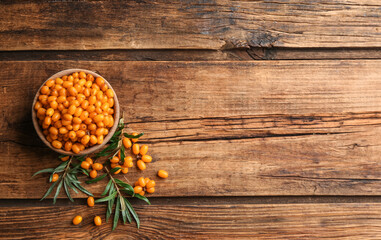 Fresh ripe sea buckthorn on wooden table, flat lay. Space for text