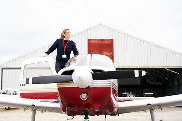 Young female pilot posing on her plane.