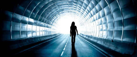 Silhouette einer Frau in einem dunklen Tunnel mit hellem Ausgang