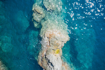 Rock and sea. Stone rock close up in the sea water. Aerial view of sea waves and fantastic Rocky coast, Italy. Clear amazing azure colour sea water with granite rocks in beach, Italy.