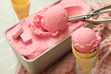 Delicious ice cream in container and wafer cones on table, closeup