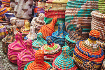 many african straw baskets on a market stand, with many colors and decorations