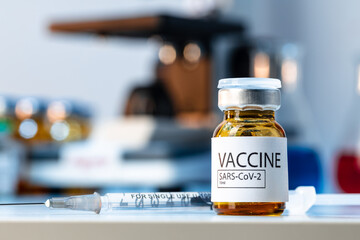 Vial of Covid-19 vaccine next to a microscope