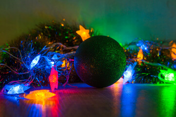 Toy balls on the Christmas tree and cones with multi-colored garlands close-up.