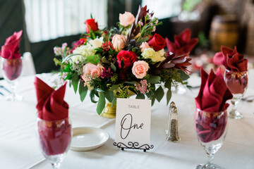Deep red flower arrangement at a wedding table, red napkins in wine glasses 