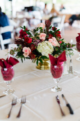 Beautiful Flower Centerpiece in Reds and Dark Colors for a Holiday Wedding, Red Napkins in Wine Glasses 