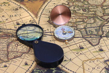 Classic round compass and magnifier on background of old vintage map of world as symbol of tourism with compass, travel with compass and outdoor activities with compass