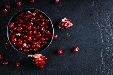 Garnet seeds in steel bowl on a dark background. Top view.